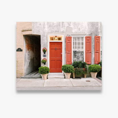 Bright red door with matching shutters and potted greenery at 25 Queen Street in Charleston – photo by Kelsey Bird