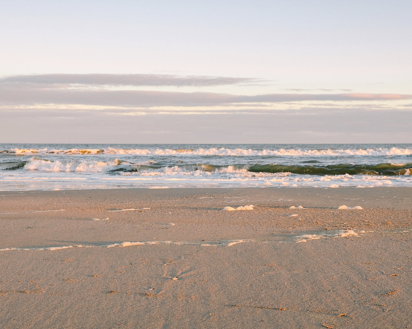 Golden sunset light reflecting on gentle waves at Folly Beach near Charleston