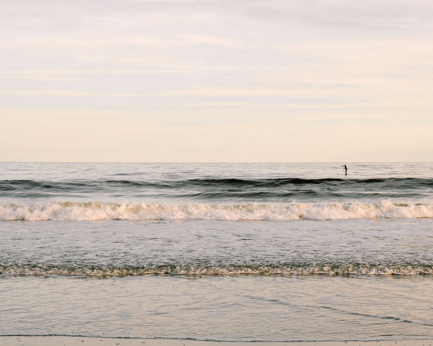 Paddleboarder on calm ocean water at sunrise in Charleston