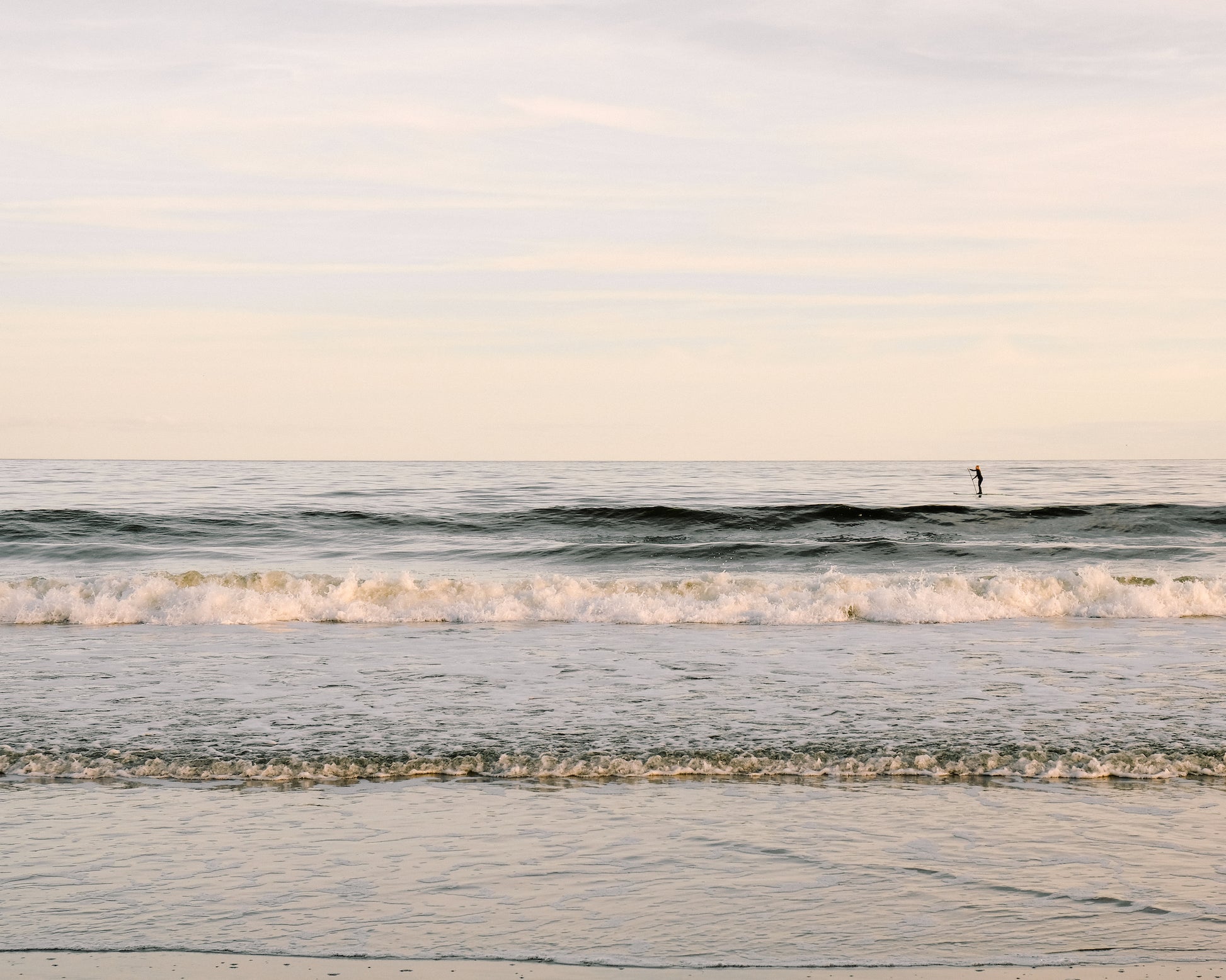 Paddleboarder on calm ocean water at sunrise in Charleston